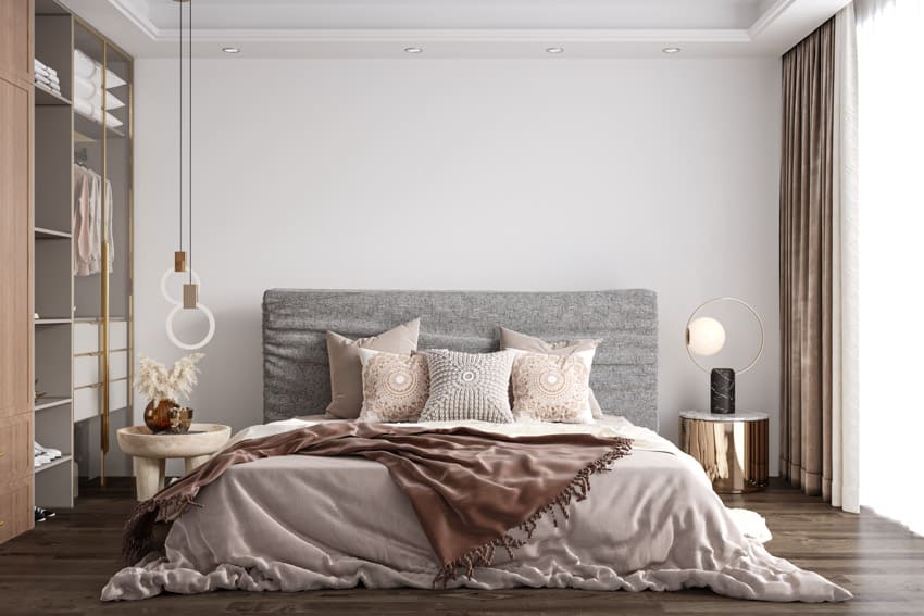 Bedroom with pillows, comforter, headboard, nightstands, lamps, wood flooring, window, and curtains