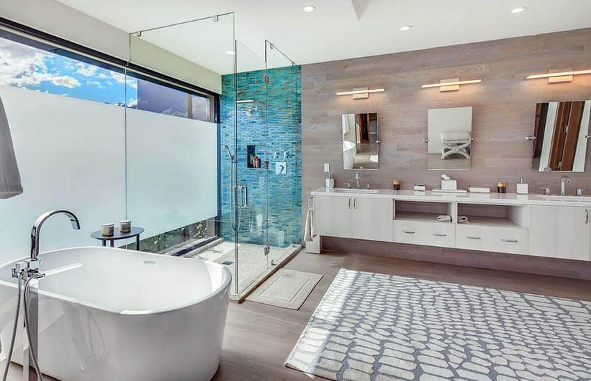 Bathroom with white tub, blue accent wall and three mirror on slate wall