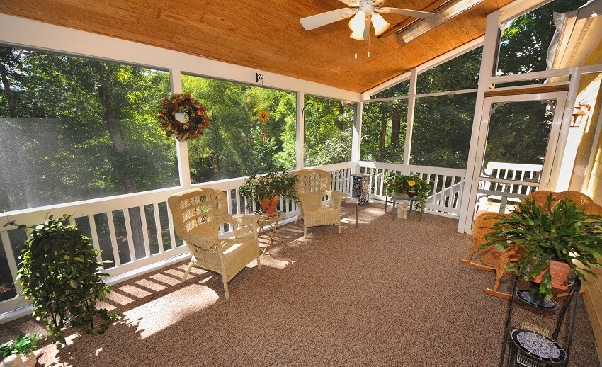Large enclosed porch with ceiling panels and rocking chairs