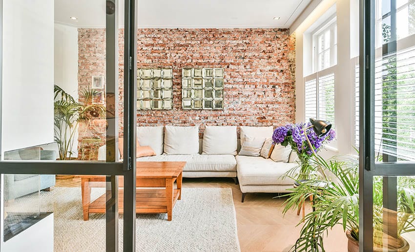 Cream sectional against brick accent wall, patterned wood flooring and large rug