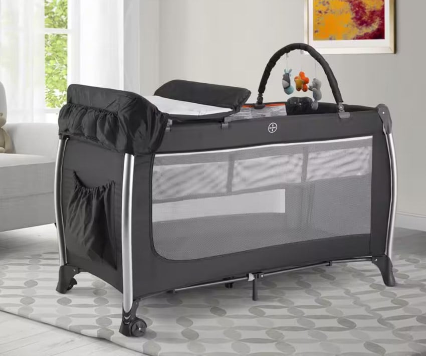 Nursery room with crib top pad, floor rug, and window